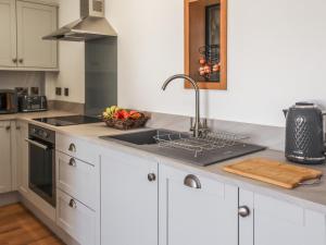 a kitchen with white cabinets and a sink with a bowl of fruit at Erddyn - Uk48860 in Llanddwywe