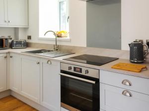 a white kitchen with a sink and a stove at Bodlyn - Uk48861 in Llanddwywe