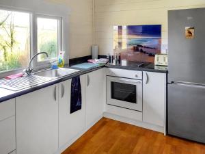 a kitchen with white cabinets and a stainless steel refrigerator at 2 The Folly's - Uk45188 in Abbotskerswell
