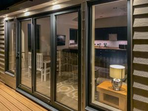 a room with sliding glass doors and a table with a lamp at Lodge With A View in Steyning