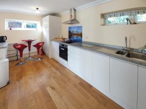 a kitchen with white cabinets and red stools at 1 The Folly's - Uk45189 in Abbotskerswell