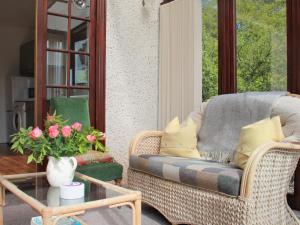 a wicker chair on a porch with a table and flowers at Forester's Cottage in Kildary