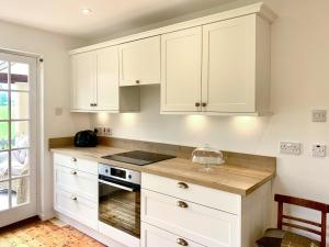 a kitchen with white cabinets and a stove top oven at Forester's Cottage in Kildary