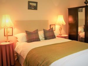 a bedroom with a large bed with two lamps at Forester's Cottage in Kildary