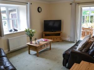 a living room with a couch and a tv and a coffee table at The Gin Gan Cottage in Ryal