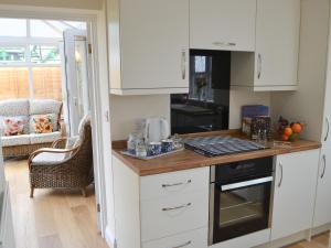 a kitchen with white cabinets and a counter top at The Gin Gan Cottage in Ryal +3 photos