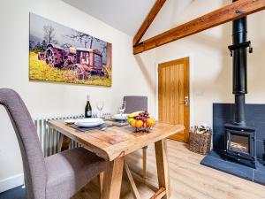 a dining room with a wooden table and a fireplace at The Parlour - Uk10958 in Burlton