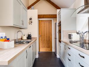 a kitchen with white cabinets and a wooden door at The Parlour - Uk10958 in Burlton