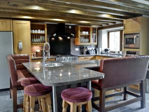 a kitchen with a large island with bar stools at Kris Kin in Criccieth