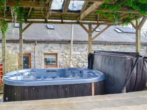 a hot tub in front of a stone building at Kris Kin in Criccieth
