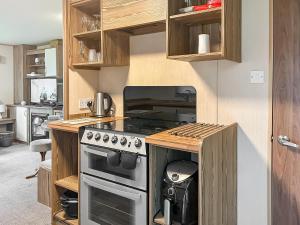 a kitchen with a stove top oven next to a counter at Kjs Holiday Haven in Ayr
