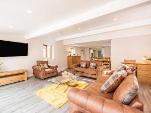 a living room with leather furniture and a flat screen tv at Stuarts Farm Barn in Westhead