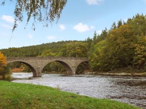 a stone bridge over a river with trees at Potarch Lodge in Kincardine OʼNeil