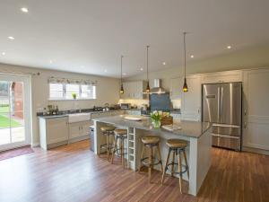 a large kitchen with a large island with bar stools at Potarch Lodge in Kincardine OʼNeil +9 photos