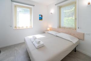 a white bedroom with a bed with two towels on it at Predore Lake View Suites in Predore
