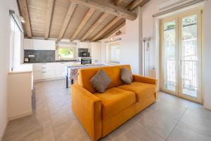 an orange couch in a living room with a kitchen at Predore Lake View Suites in Predore