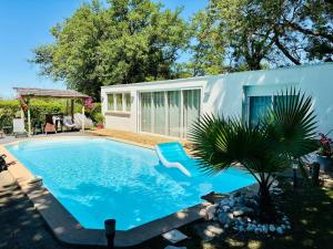 a swimming pool with a chair in front of a house at Échappée Mistral - Jacuzzi Privé & Brasero in Eyragues