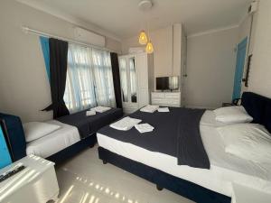 a hotel room with two beds and a television at Olivento Pansiyon in Ayvalık +8 photos
