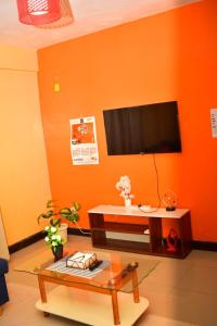 a living room with an orange wall with a flat screen tv at Hecahomes in Kericho +7 photos