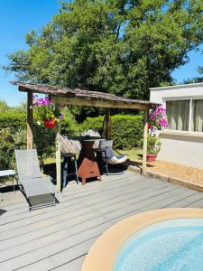 a wooden deck with a table and chairs next to a swimming pool at Échappée Mistral - Jacuzzi Privé & Brasero in Eyragues