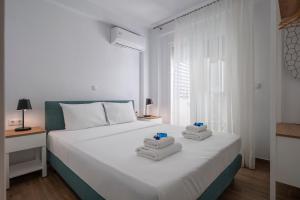 a bedroom with a white bed with towels on it at SLV Roxani Apartment in Ofrínion