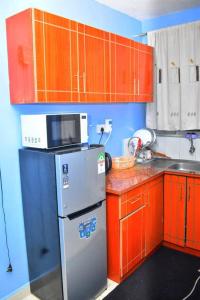 a small kitchen with a refrigerator and red cabinets at Hecahomes in Kericho