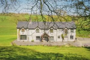 a white house in the middle of a field at Ceunant in Llanfair Caereinion