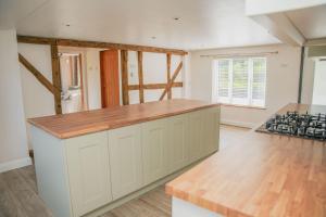 a kitchen with white cabinets and a wooden counter top at Ceunant in Llanfair Caereinion +70 photos