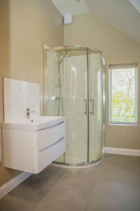 a bathroom with a glass shower and a sink at Ceunant in Llanfair Caereinion