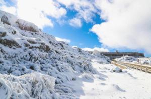 a snow covered mountain with a building in the background at Interbeira Sandomil River Cottage in Seia