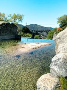 a river with rocks and a bridge in the background at Interbeira Sandomil River Cottage in Seia