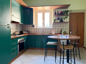 a kitchen with green cabinets and a table with chairs at Cuore di Nozzano Castello in Lucca