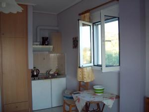 a kitchen with a table and a sink and two windows at Oasis studios in Psili Ammos