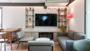 a living room with a couch and a tv on a wall at Campanile NATURE - Brive-la-Gaillarde in Brive-la-Gaillarde