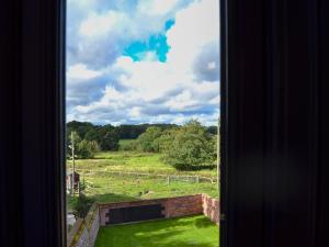 a window with a view of a field and trees at Jupiter Barn in Swafield