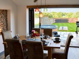 a dining room with a table and chairs and a large window at Jupiter Barn in Swafield