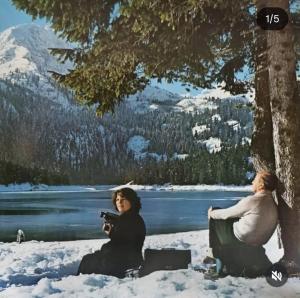 two women sitting in the snow under a tree at Sušica Apartman in Kovačka Dolina