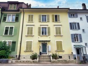 a yellow house with green shutters and stairs at Casa Maria Apartments Solothurn in Solothurn