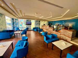 a restaurant with blue chairs and tables and a bar at Saffron Hotel and Lounges in Muscat