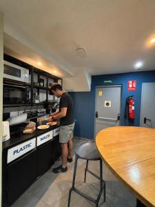 a man standing in a kitchen preparing food at Sun & Moon Hostel in Barcelona