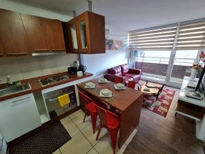 a kitchen with a table and red chairs in a room at Departamentos Concepcion Centro in Concepción