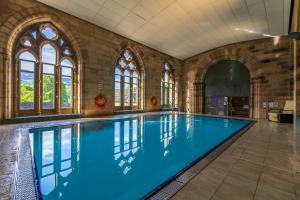a large swimming pool in a building with windows at Loch Ness Abbey Cottages in Fort Augustus