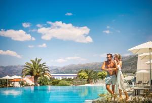 a man and a woman standing next to a swimming pool at Valamar Lacroma Hotel in Dubrovnik