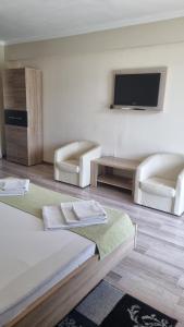 a bedroom with two white chairs and a flat screen tv at Casa Aless Eselnita Adults Only 14 plus in Eşelniţa