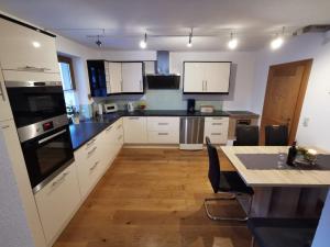 a kitchen with white cabinets and a table with chairs at Ferienwohnung Magdalena in Stumm