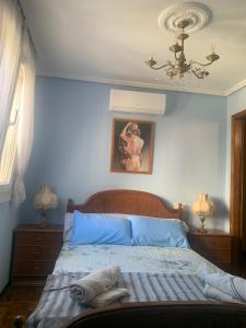 a bedroom with a bed with blue sheets and a chandelier at O recuncho - Alojamiento tranquilo cerca de Ribeira Sacra y Ourense in Maceda