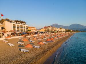 a beach with a bunch of chairs and umbrellas at Olimpia Hotel in Fethiye