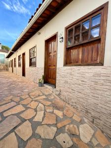 a building with a wooden door and a stone sidewalk at Recanto Canuto in Diamantina