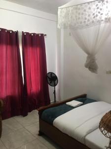 a bedroom with a bed with red curtains at Meublé de toursime L'Escale in Yaoundé +14 photos