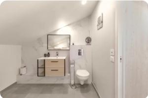 a white bathroom with a sink and a toilet at Chambre Attrape rêves in Sainte-Geneviève-des-Bois